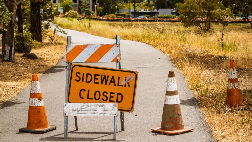A closed sidewalk with caution sign and cones indicates a maintenance area.