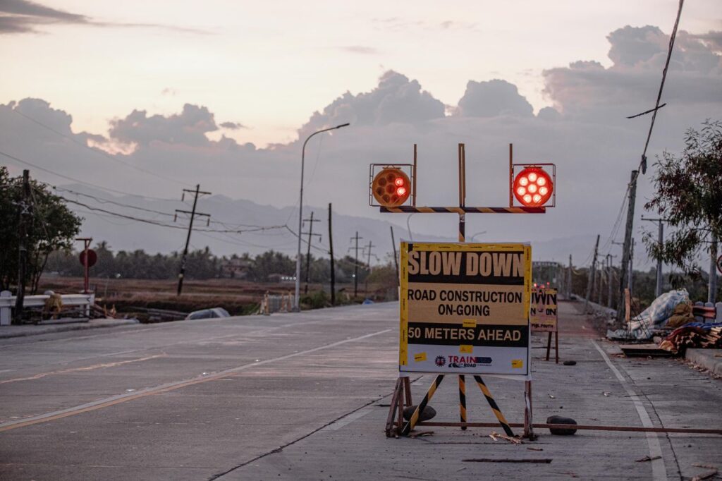 Bright signboard with inscription and shiny signs on asphalt roadway during repairing process in evening under cloudy sky